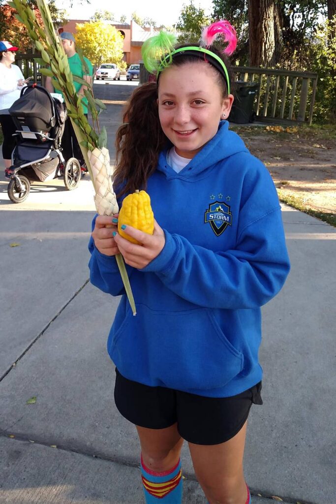 girl holding lulav and etrog outside