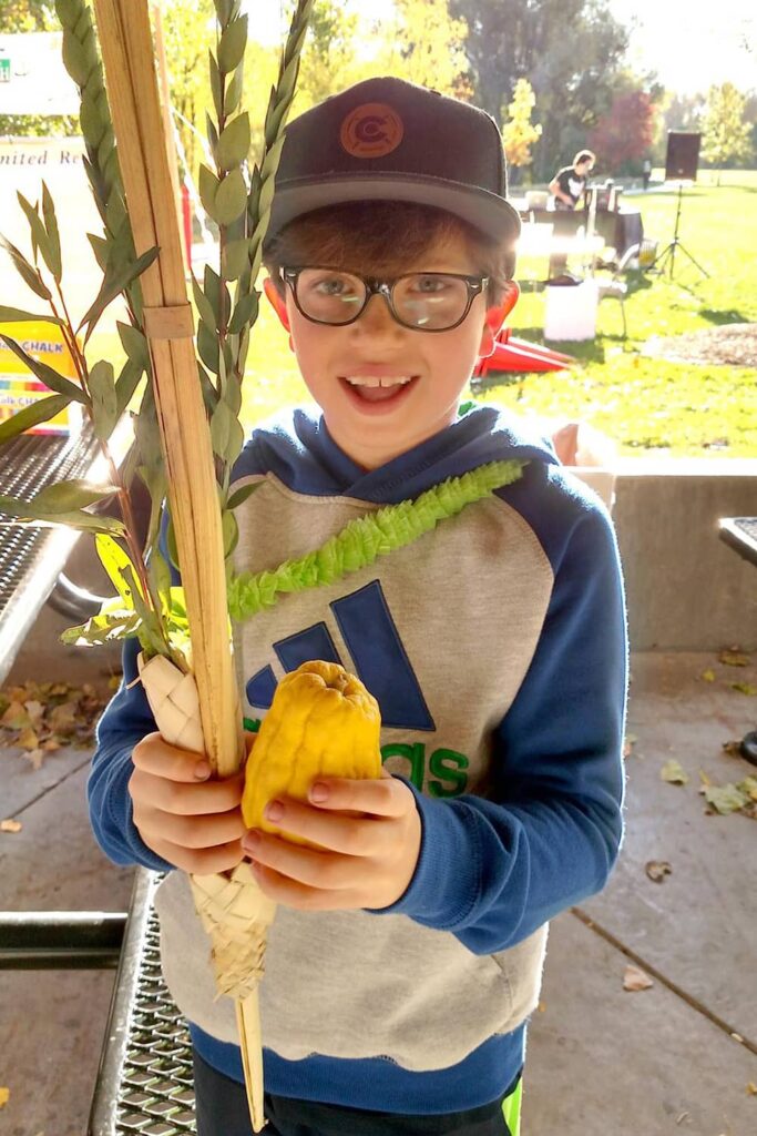 boy holding lulav and etrog outside
