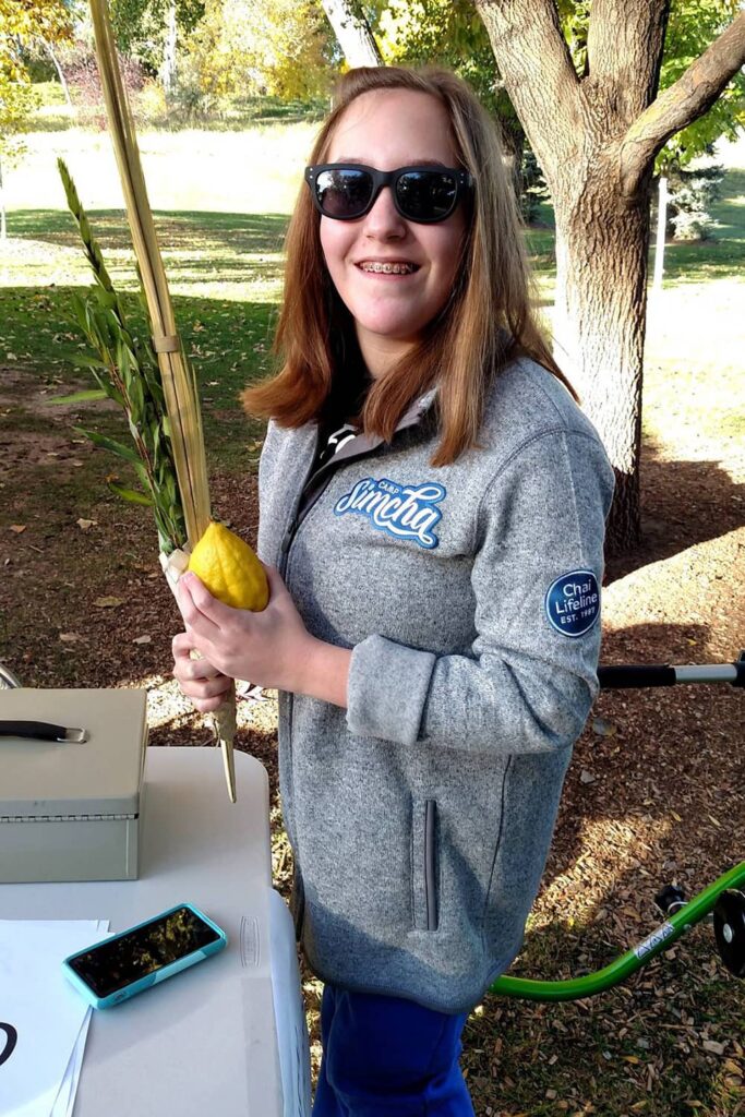 teenage girl holding lulav and etrog outside